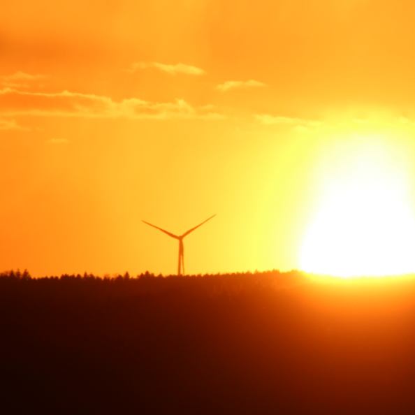 Oranger Sonnenuntergang, am Horizont zwei Windkraftanlagen