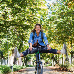 Symbolbild: Eine Frau auf dem Fahrrad radelt durch eine Allee