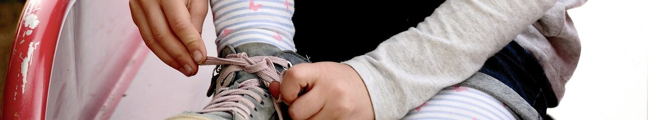 Ein Kind bindet die Schnürsenkel