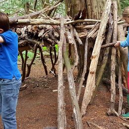 Zwei Kinder im Wald bauen eine Hütte