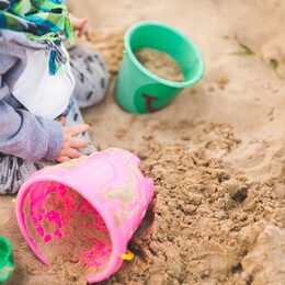 Kind im Sandkasten mit Eimerchen