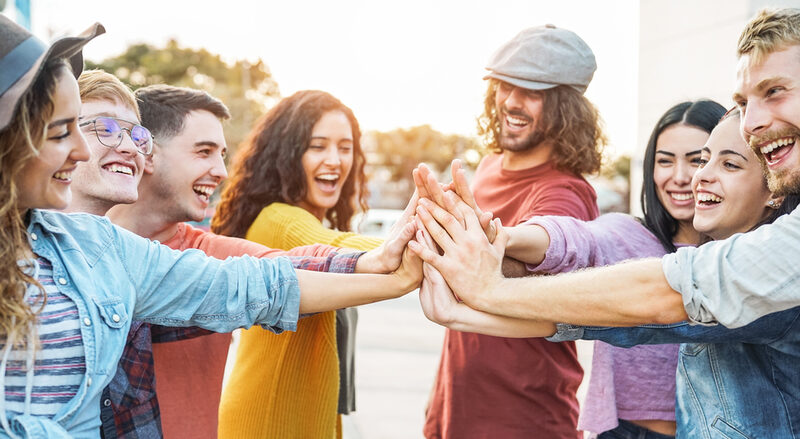 Young friends stacking hands outdoor - Happy millennial people having fun joining and celebrating together - Friendship, empowering, teamwork, partnership and youth lifestyle concept