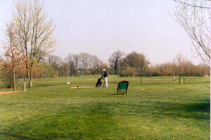 ein einzelner Golfspieler mit Caddy auf einem Golfplatz. Junge Bäume, viel Grün
